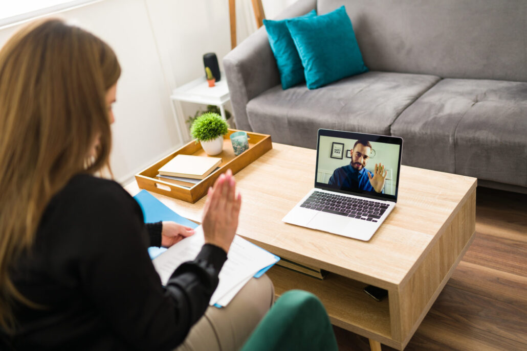 Unrecognizable woman at home saying hello to her virtual associate on a video call on the laptop